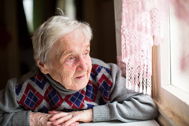 An elderly woman looks out the window.